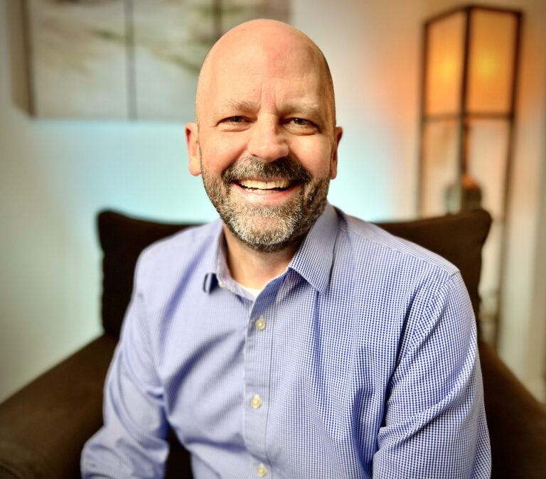 Davis in a blue shirt smiling broadly at the camera