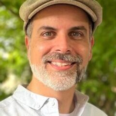 Paul-Green Paul smiling wearing a light collared shirt and a hat