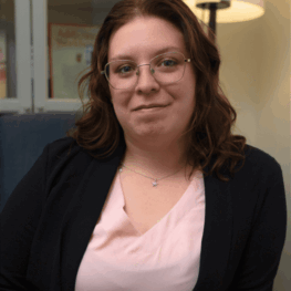 Taylor-VOH-Pic-1-768x768 Taylor wearing a black cardigan over a pink v-neck shirt, smiling lightly at the camera