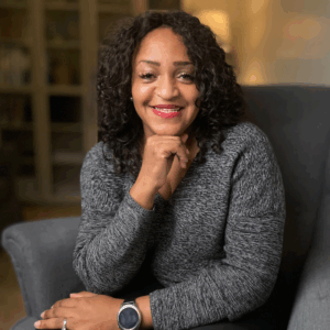 Andrea posed seated in a chair with her chin rested on her hand